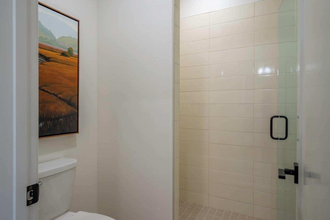 Shower enclosure featuring a frameless glass door with matte black hardware, horizontal subway tile walls, and a tiled floor