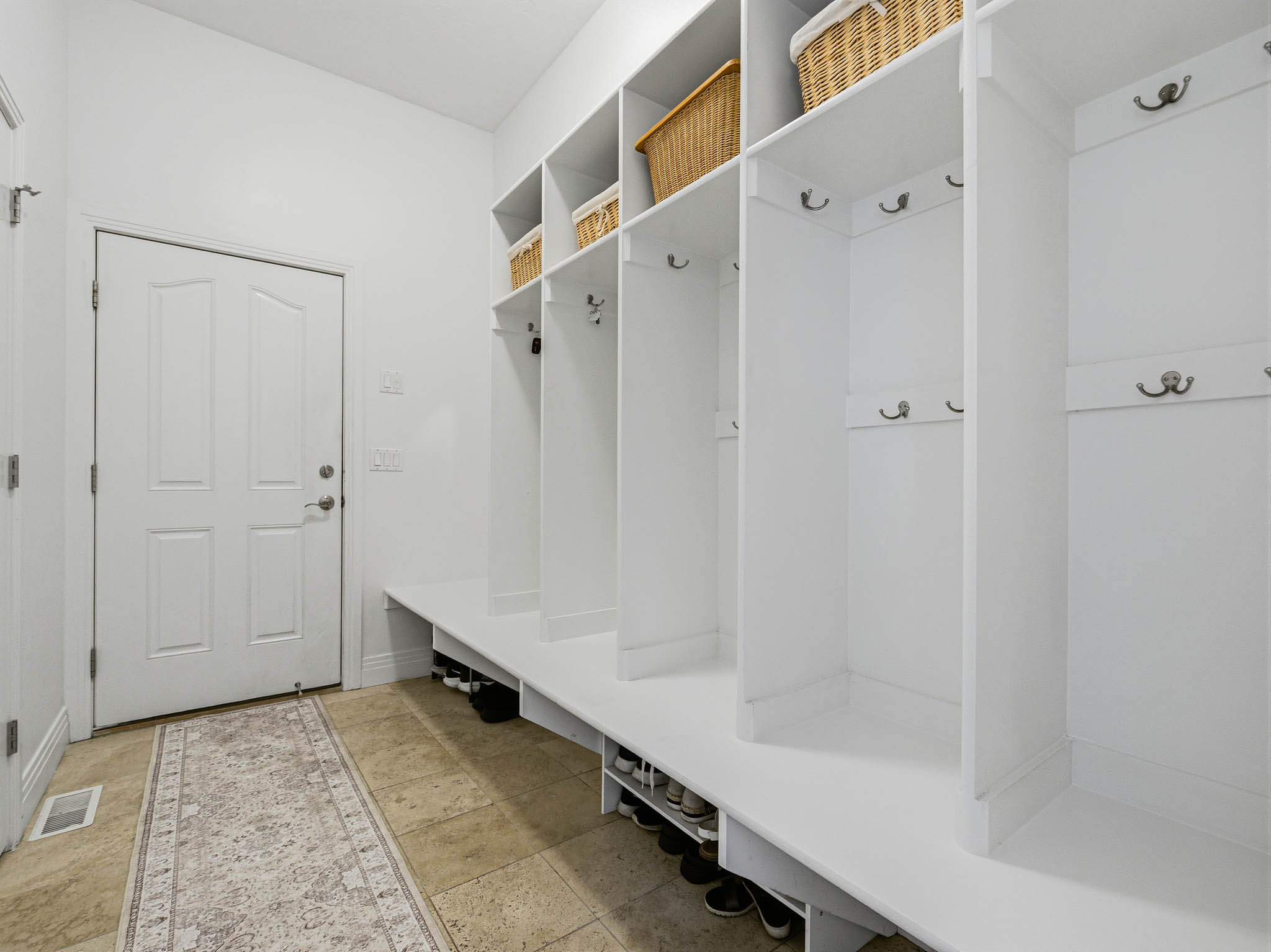 Built-in cubbies and shelving featuring multiple coat hooks and shoe storage