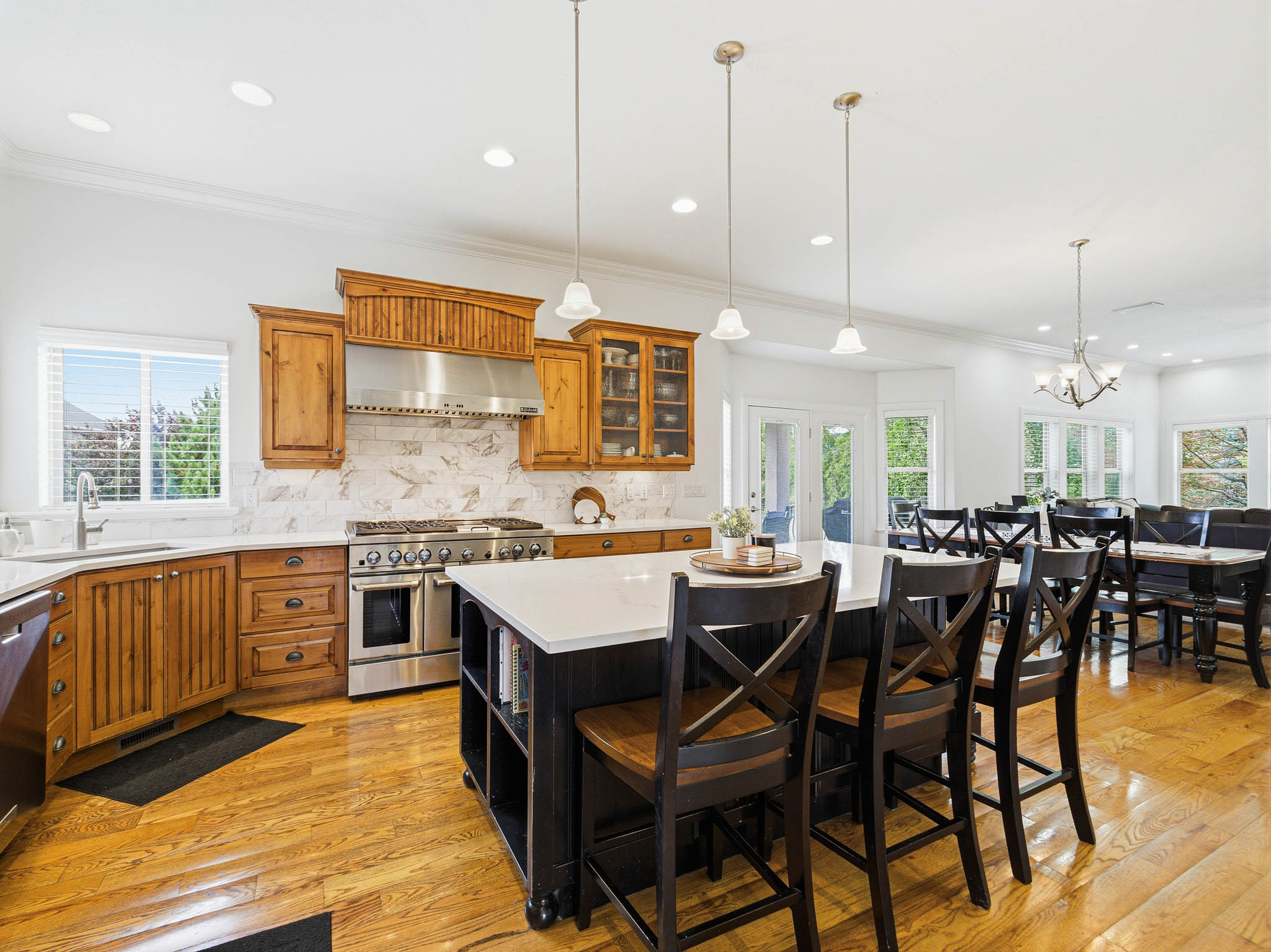 Spacious kitchen featuring warm wood cabinetry, stainless steel range with matching hood, and light-toned countertops
