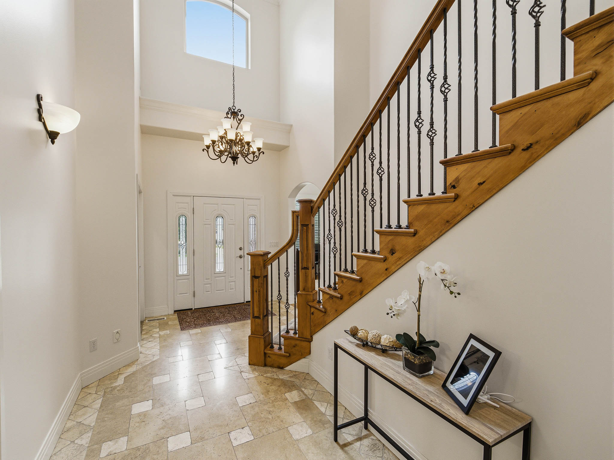 Two-story entryway featuring a grand staircase with wood treads and wrought iron balusters