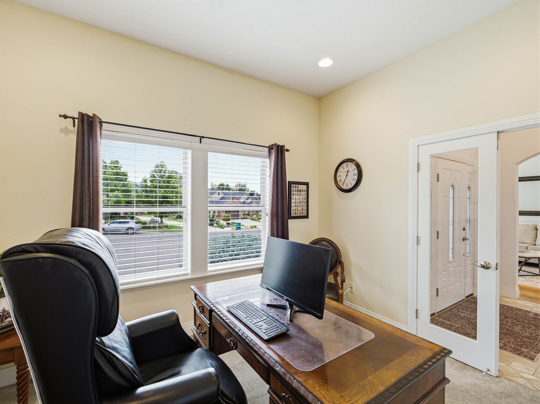 Bright room featuring two large windows with blinds, a tray ceiling, recessed lighting, and a glass-paneled door
