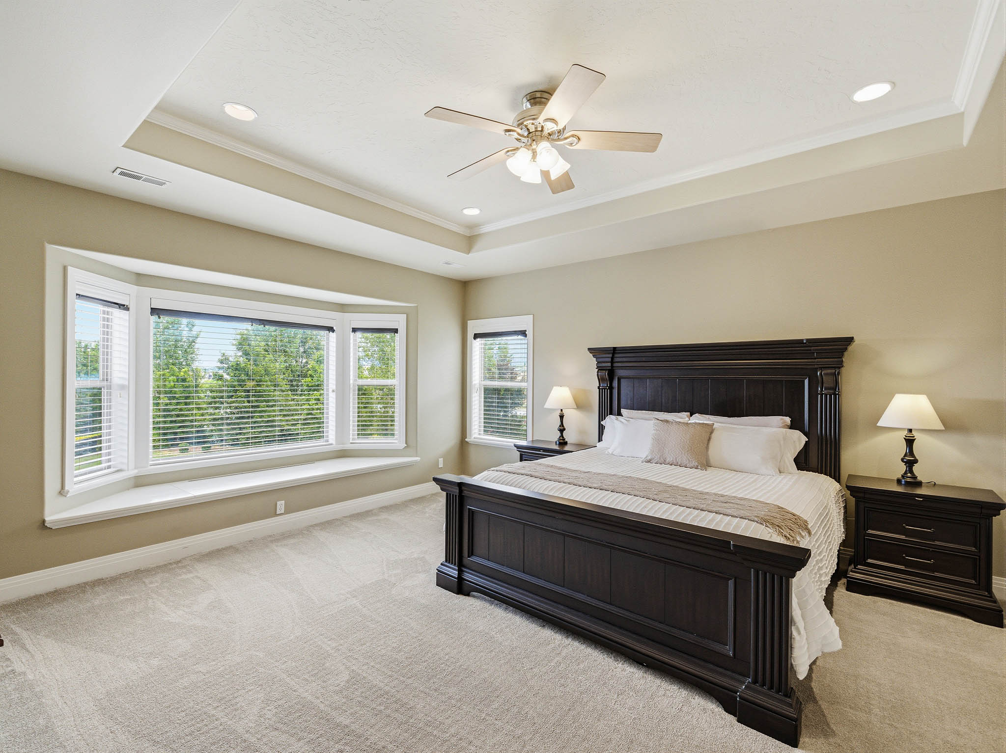Spacious room featuring a tray ceiling with recessed lighting, crown molding, and a ceiling fan