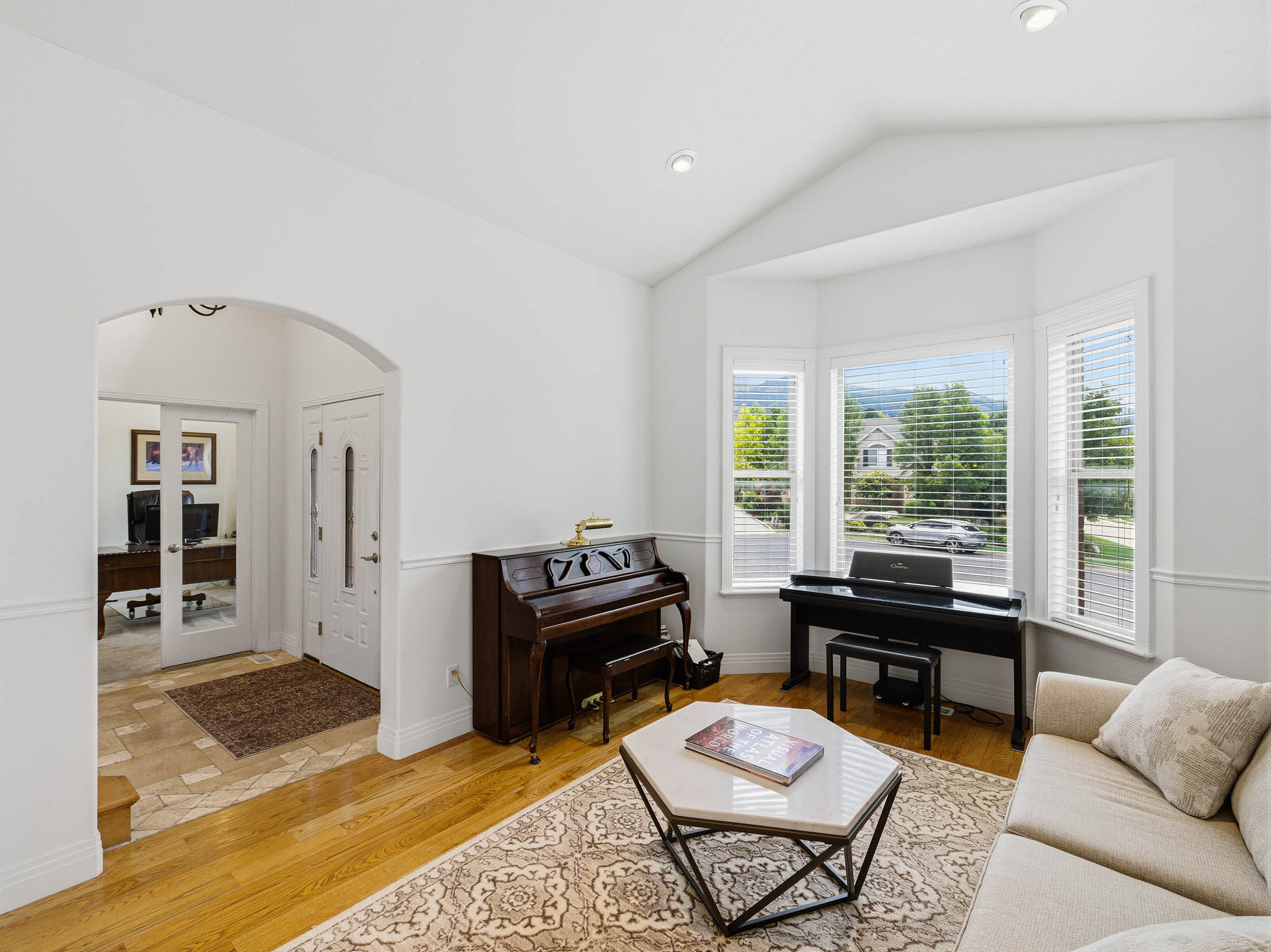 Bright living space featuring a vaulted ceiling and bay windows with exterior views
