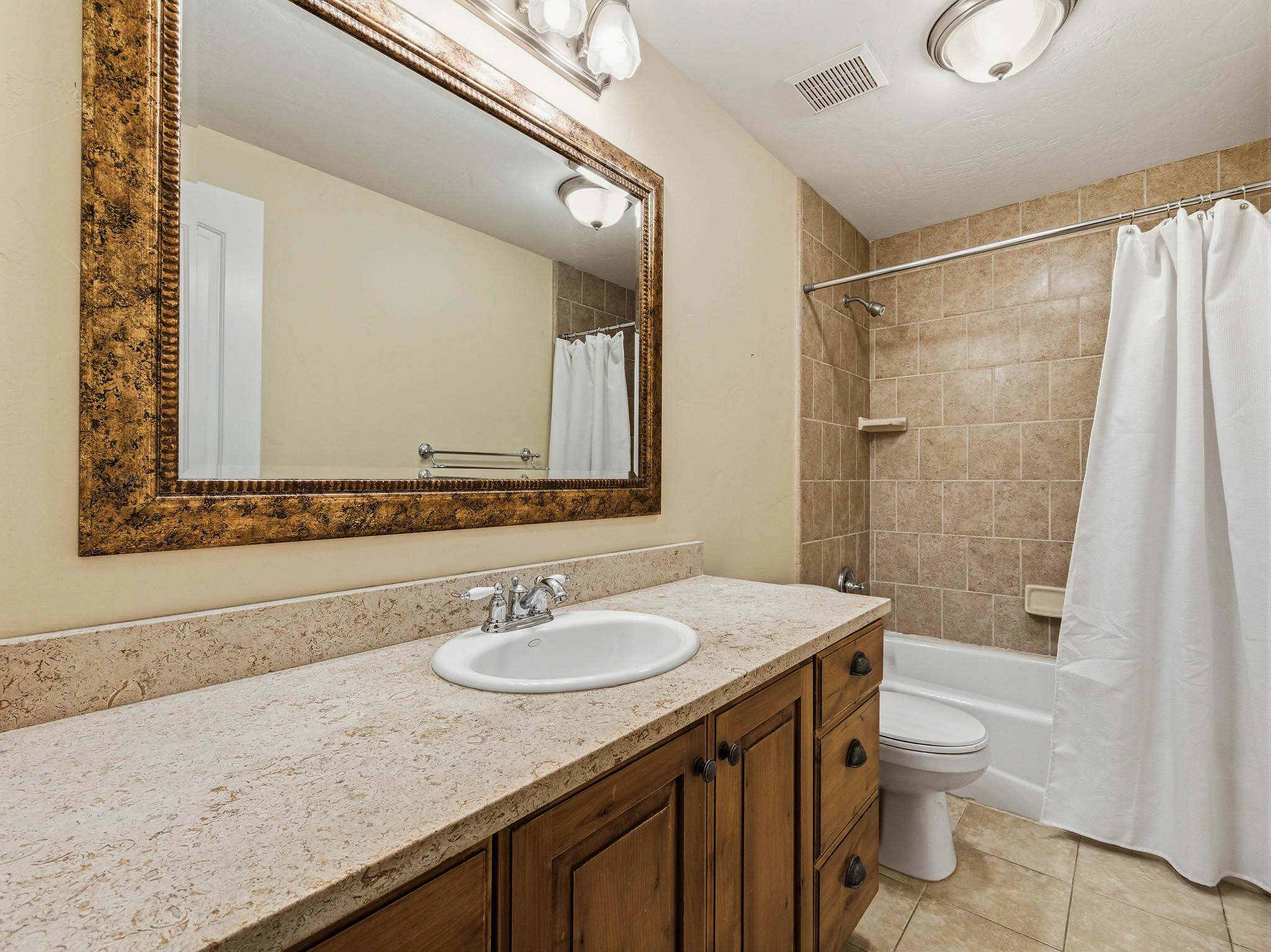 Bathroom featuring a vanity with an integrated sink, a light-toned countertop, and wood cabinetry