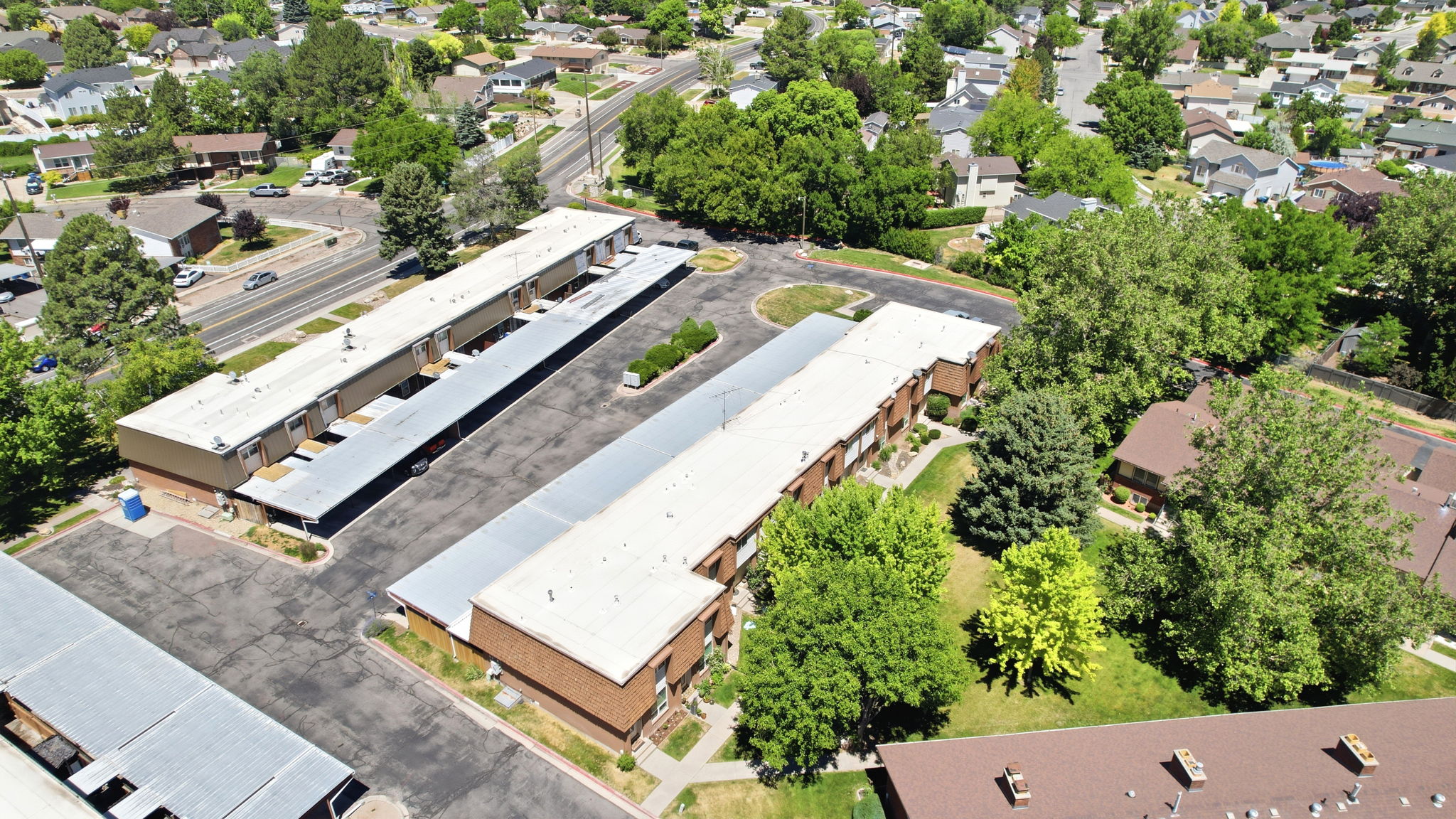 Multi-building property featuring brick exterior construction, ample surface parking, covered parking structures, and mature landscaping