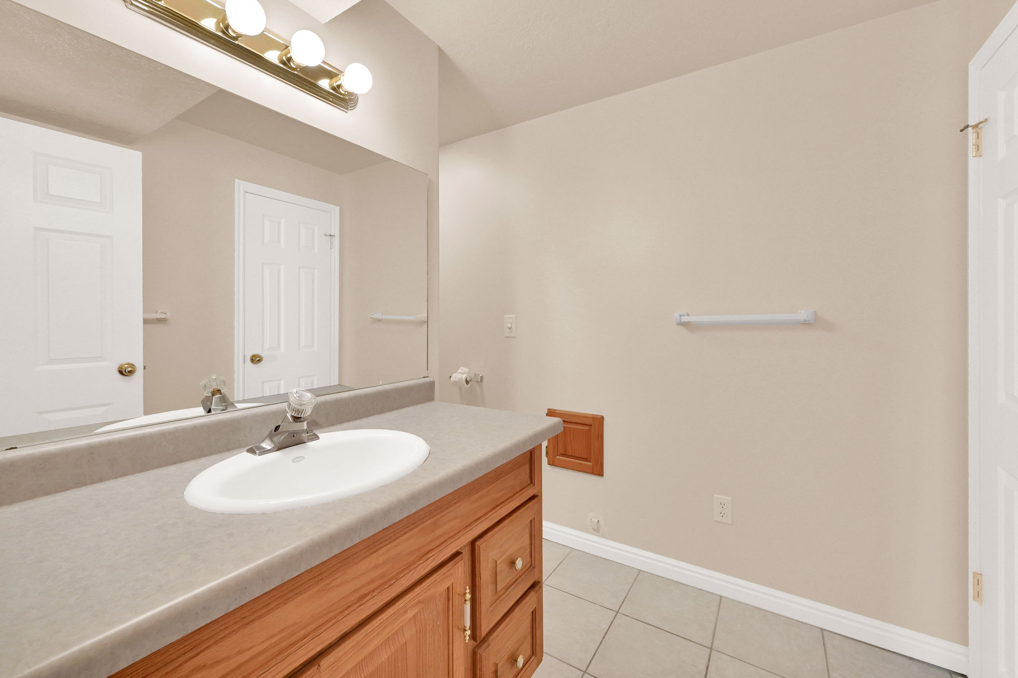 Bathroom featuring a wood-finish vanity with a single basin sink and a gray countertop