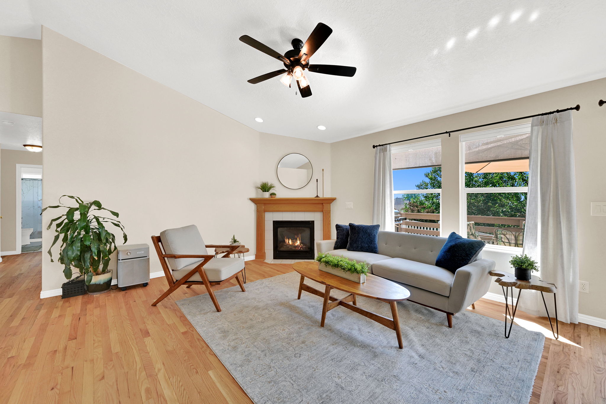 Bright living space featuring hardwood flooring, a corner fireplace with a wood mantel, and multiple windows
