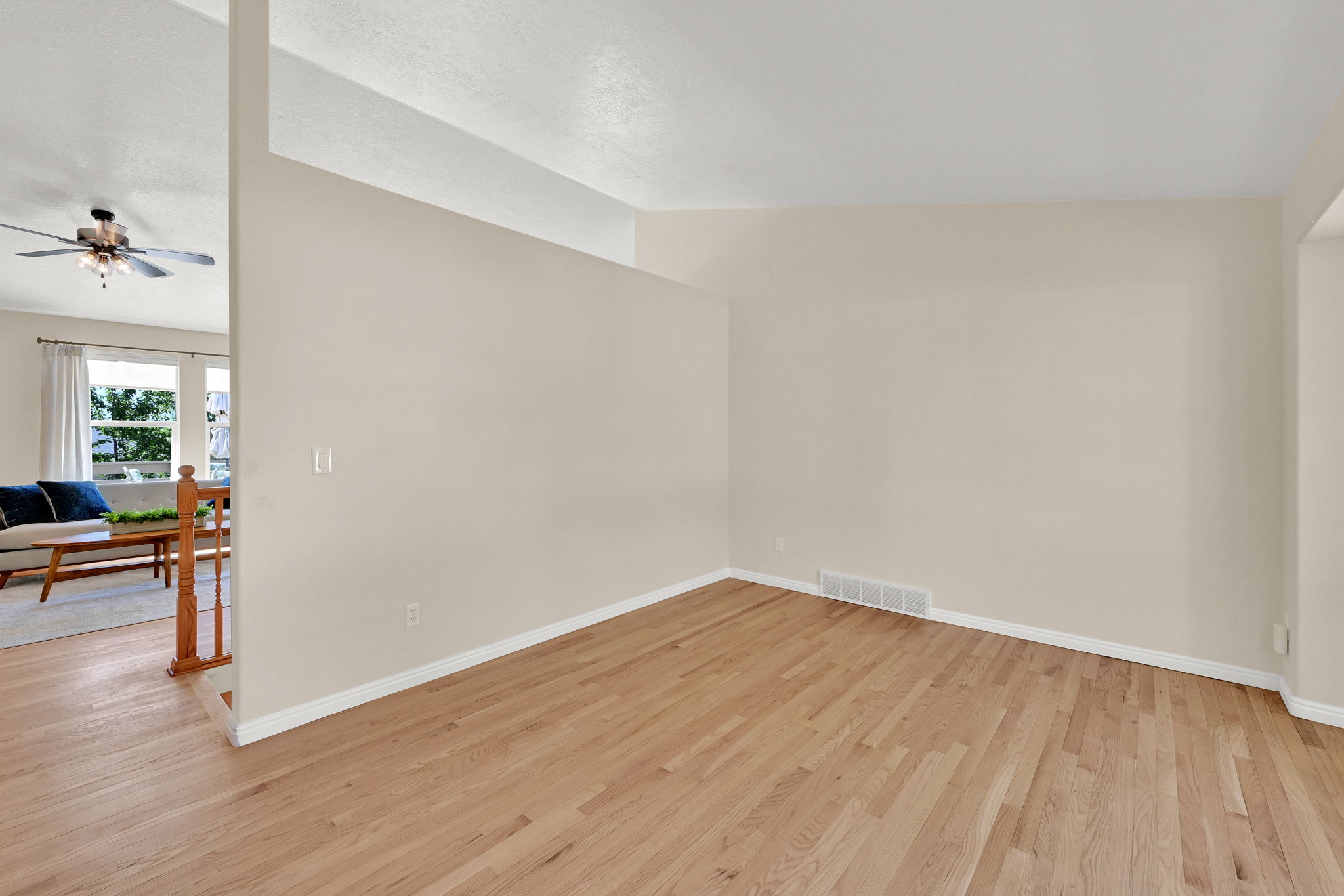 Spacious room with wood-finish flooring, light neutral wall paint, and white baseboards