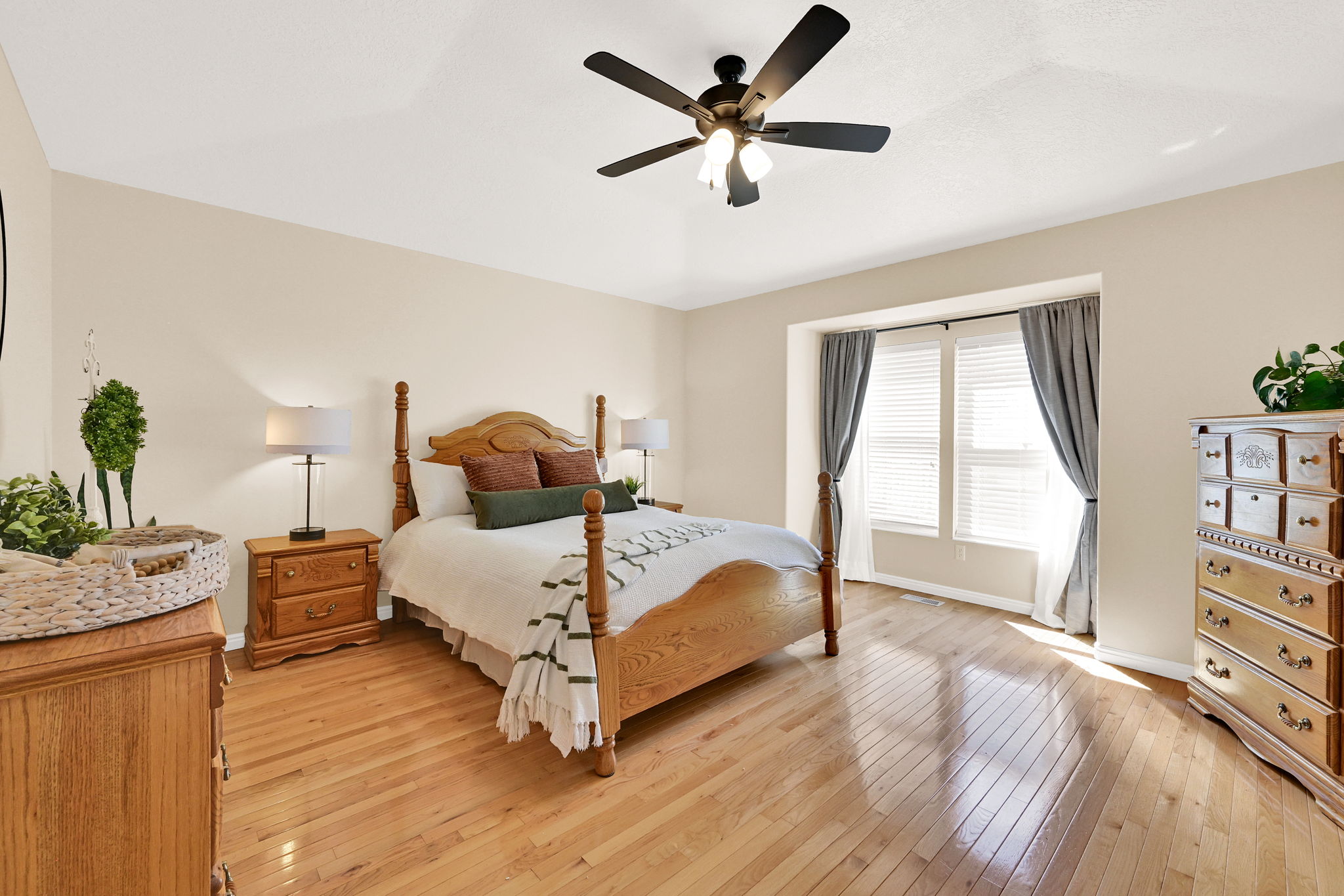 Bedroom featuring light wood-finish flooring, a tray ceiling, and a ceiling fan with integrated lighting