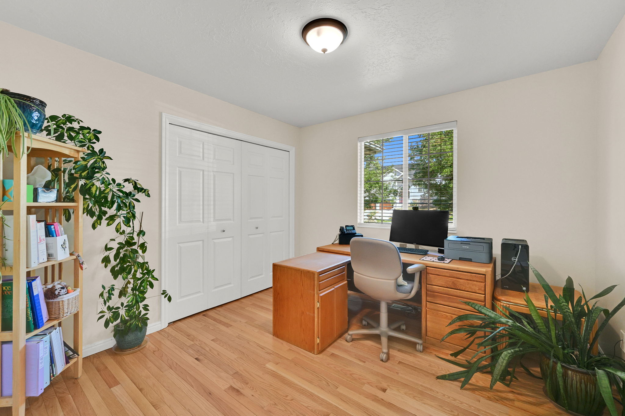 Room featuring wood-finish flooring, light-toned walls, and a window with blinds