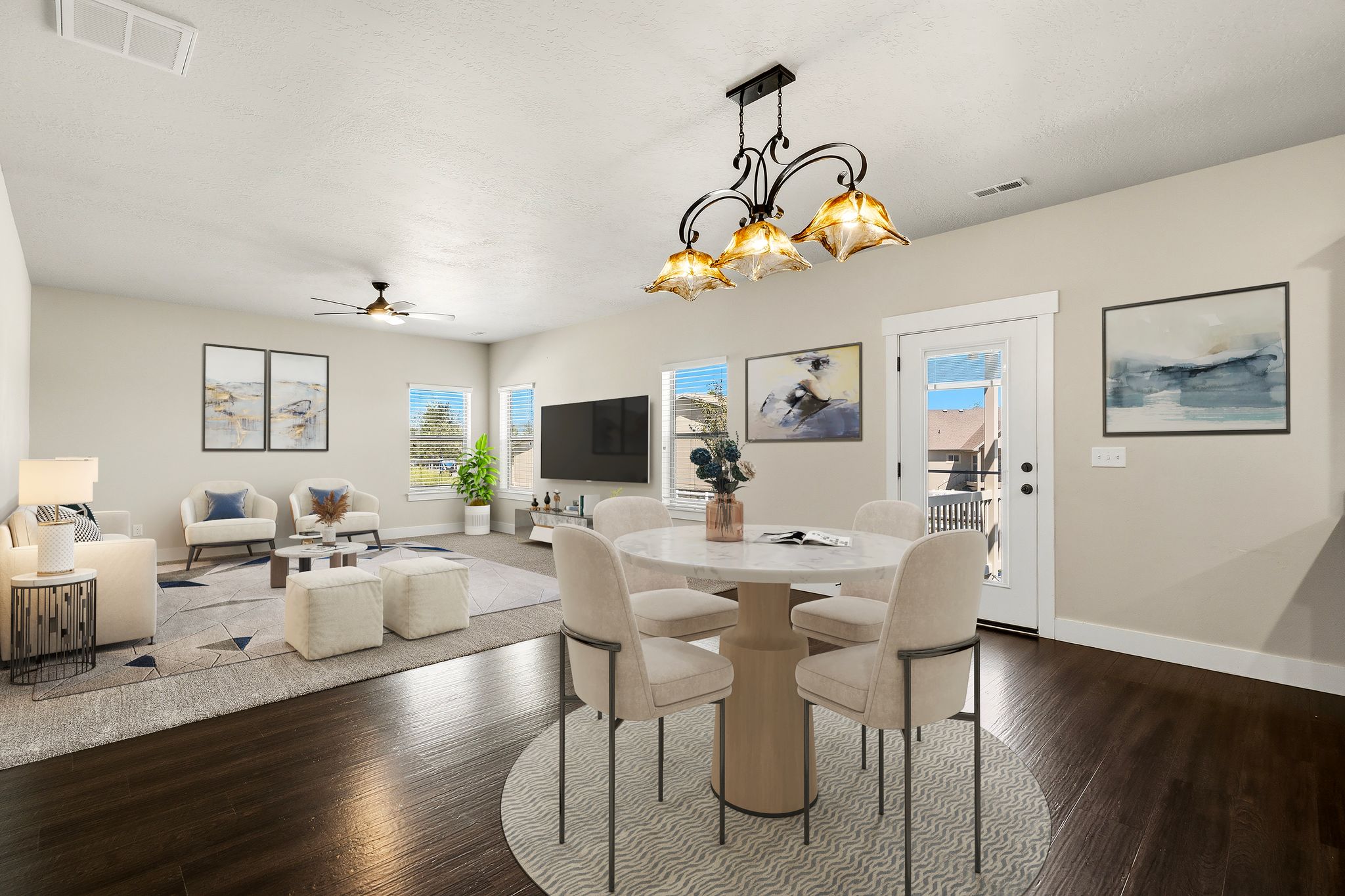 VIRTUAL FURNITURE STAGING shows open-concept living and dining area featuring dark wood-finish flooring in the dining space, a circular dining table with a four-light chandelier, a ceiling fan in the living area, and multiple windows for natural light