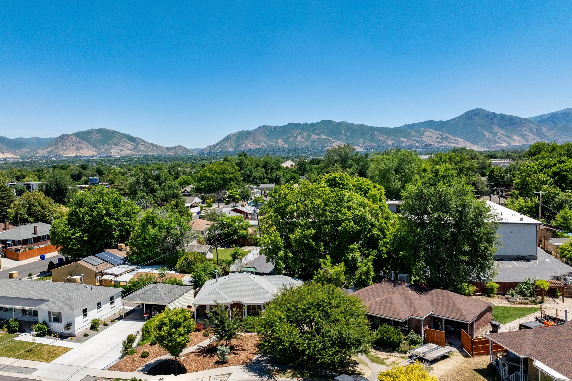 Expansive mountain range backdrop framing a residential area with mature trees and varied architectural styles