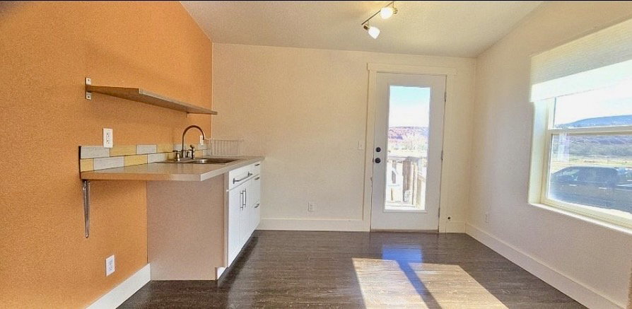 Compact kitchen area featuring a stainless steel sink, a contemporary faucet, and white cabinetry