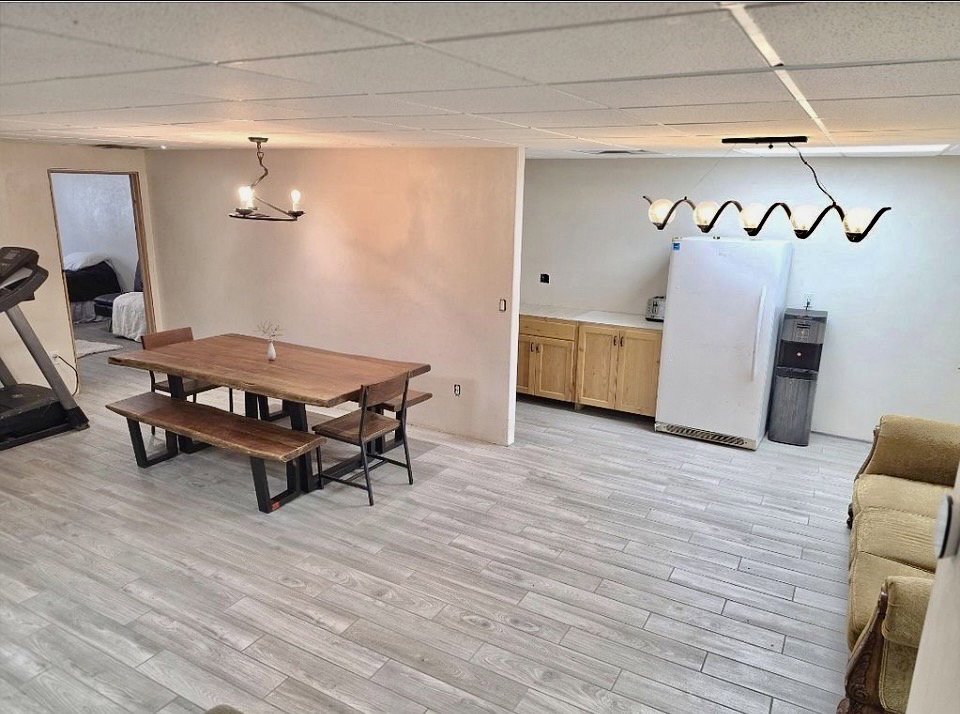 Spacious room featuring wood-finish flooring, a drop ceiling, and a built-in base cabinet with countertop space