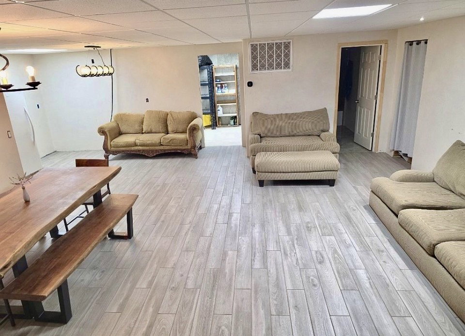 Spacious room featuring wood-finish flooring, a contemporary linear chandelier, and recessed lighting