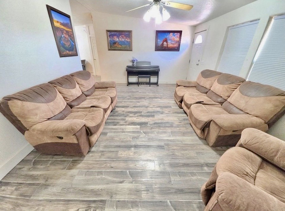 Spacious interior featuring wood-finish flooring, a ceiling fan, and white walls