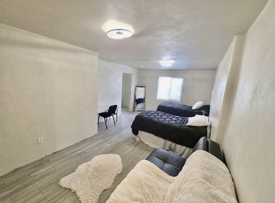 Spacious room featuring light-toned wood-finish flooring, white textured walls, and a recessed window for natural light
