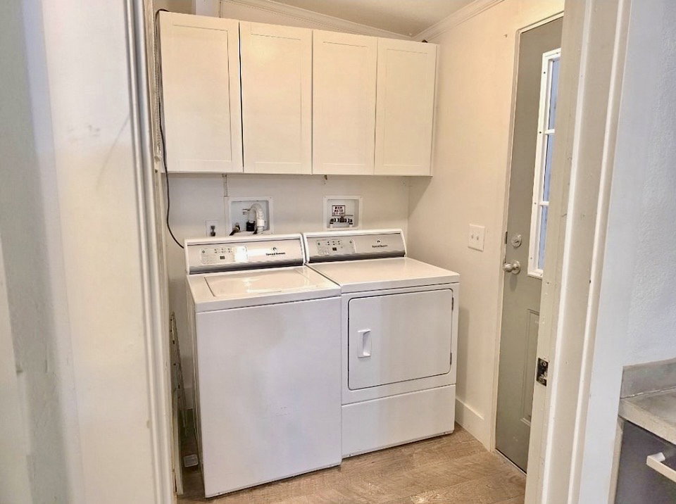 Dedicated laundry area featuring upper cabinetry, tile flooring, and exterior door access