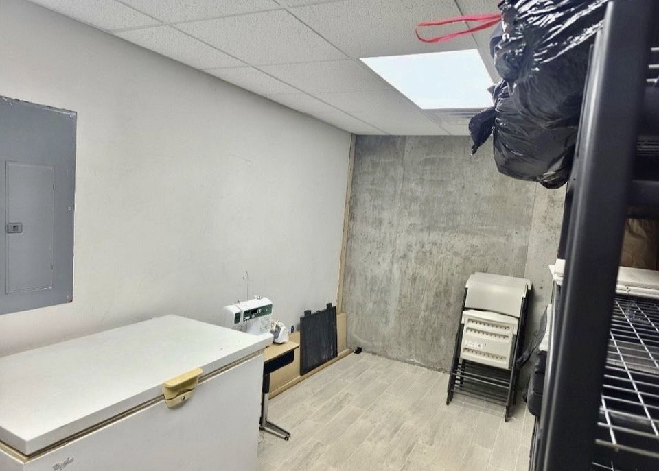 Utility room featuring a drop ceiling, light-toned walls, and wood-finish flooring