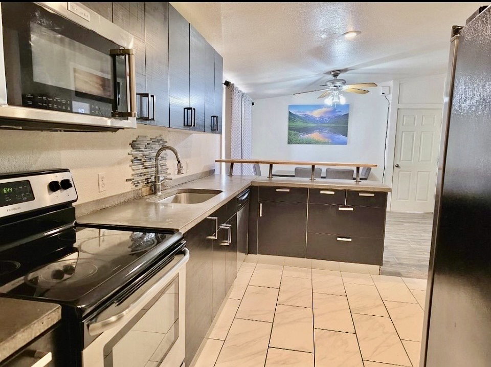 Contemporary kitchen featuring dark wood-finish cabinetry, stainless steel appliances, and concrete-finish countertops