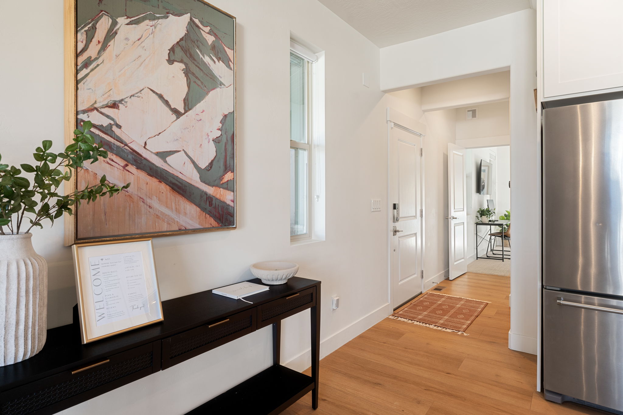Entryway featuring light wood-finish flooring, a contemporary black console table with drawers, and a white paneled door