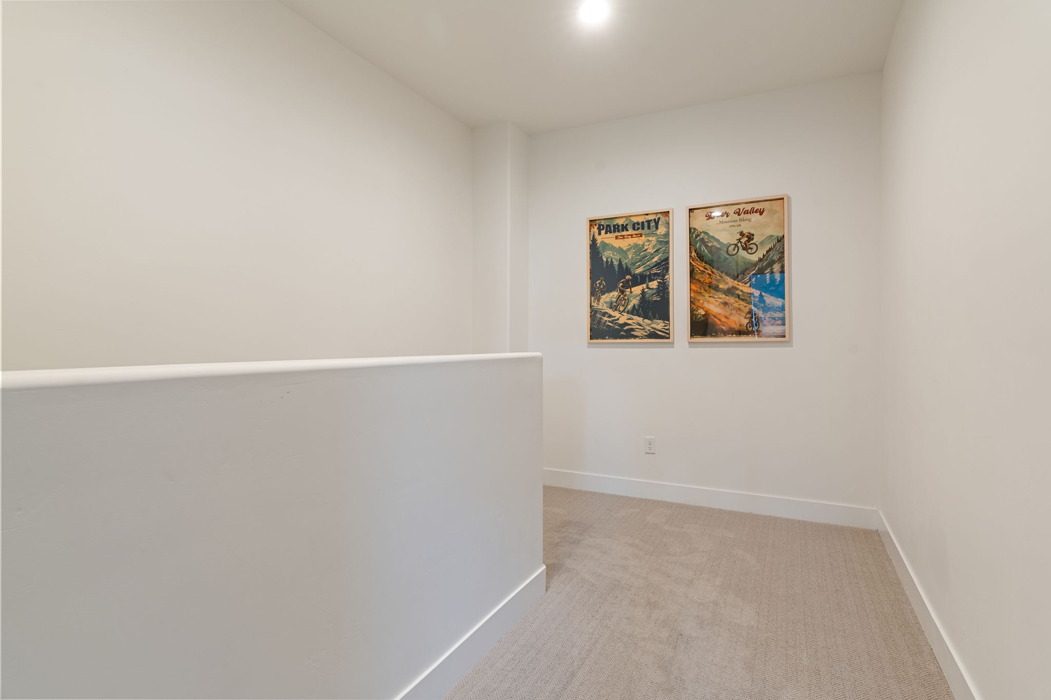 Carpeted hallway featuring a white half-wall and contemporary baseboards