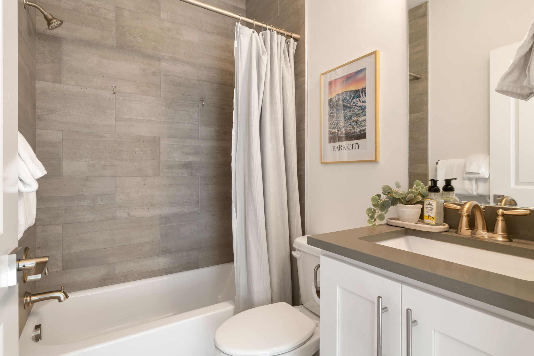 Bathroom featuring a white vanity with a gray countertop, an undermount sink, and brass-finish fixtures