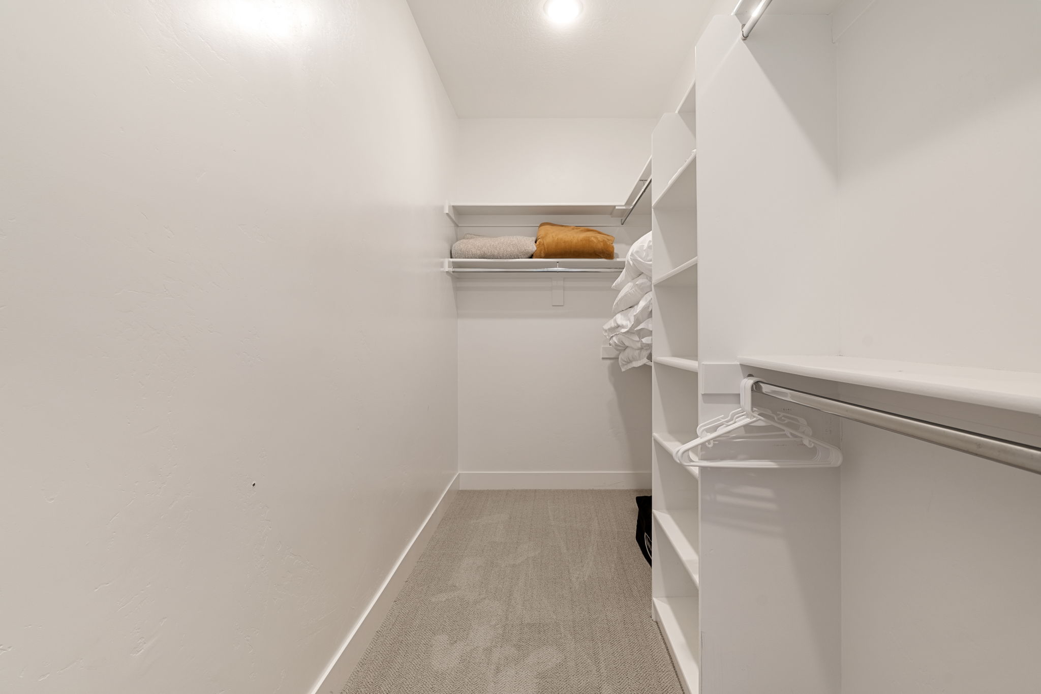 Walk-in closet featuring built-in shelving, hanging rods, and recessed lighting