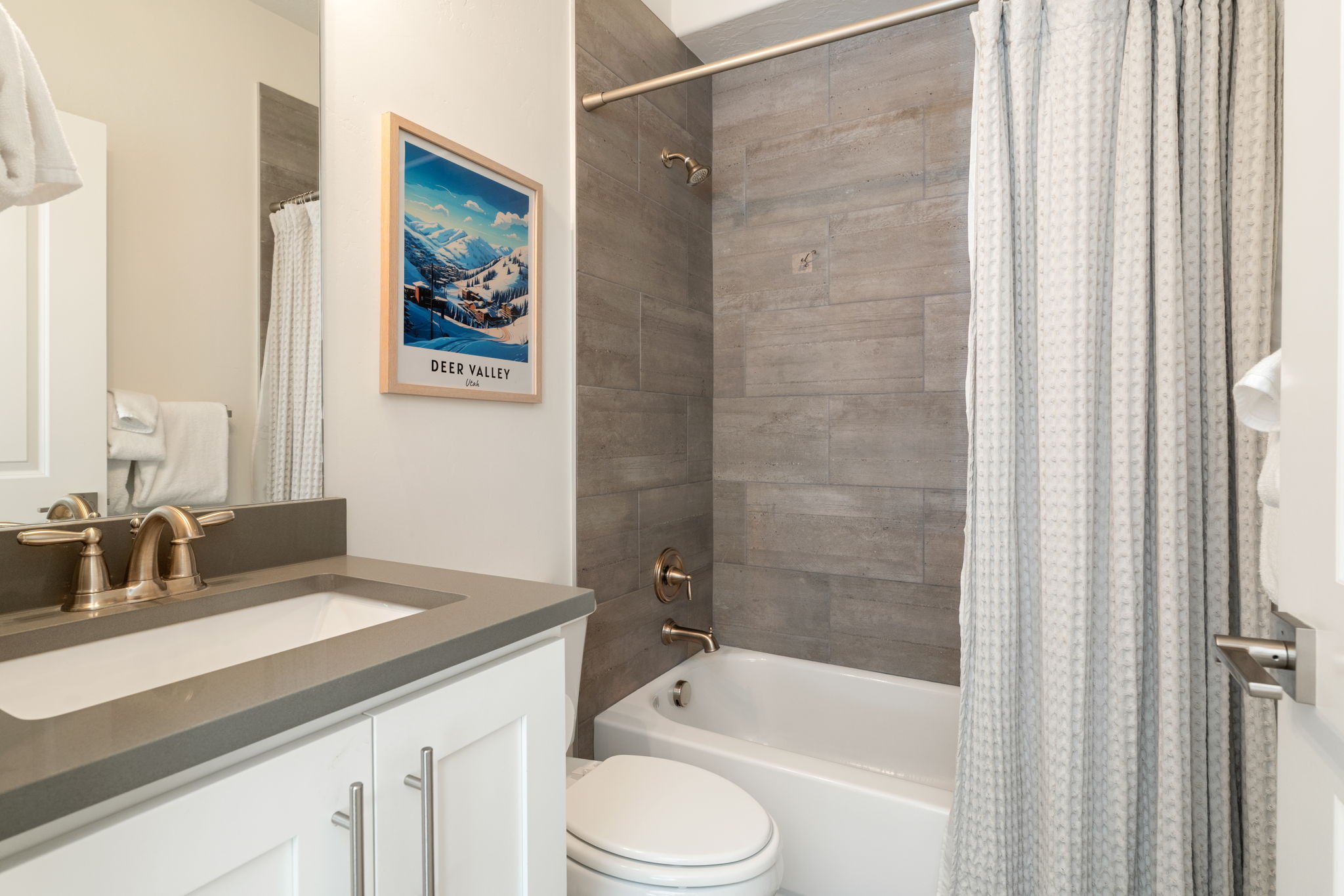Bathroom featuring a white vanity with a dark countertop, an undermount sink, and brushed gold hardware