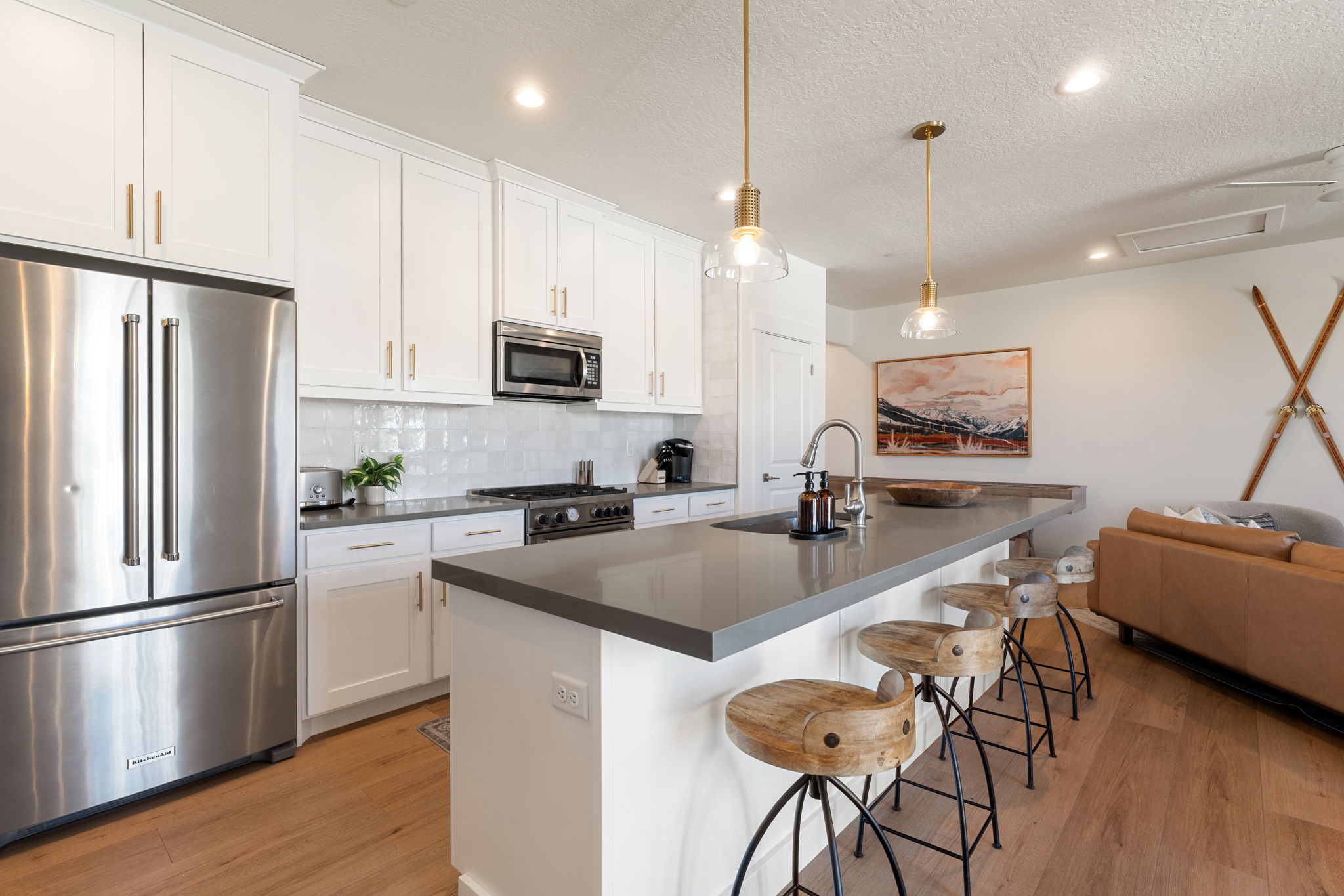 Kitchen featuring white cabinetry, stainless steel appliances, a tile backsplash, and a large island with a dark countertop
