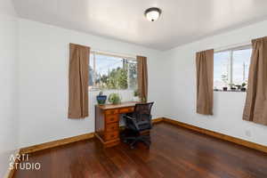 Bright room featuring rich wood-finish flooring, white walls, and wood baseboards