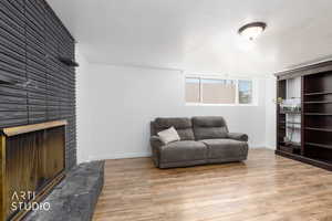 Spacious room featuring a stone-clad fireplace with hearth, wood-finish flooring, and a built-in dark wood bookcase