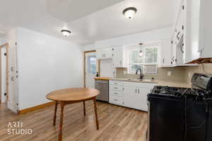 Bright kitchen featuring white cabinetry, light countertops, stainless steel dishwasher, and wood-finish flooring