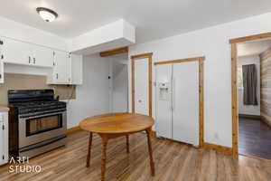 Kitchen featuring wood-finish flooring, white cabinetry with dark hardware, a stainless steel range, and a white refrigerator