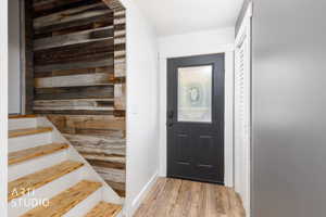 Entryway featuring a dark paneled door with decorative glass, wood-finish flooring, and a contrasting accent wall with horizontal wood planks