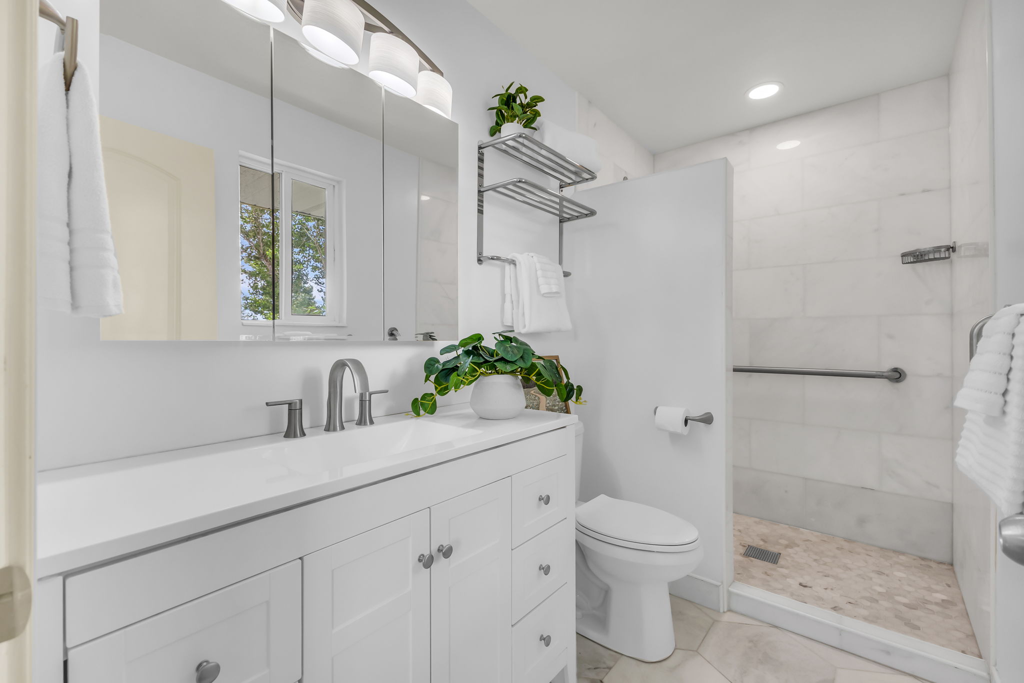 Bright bathroom featuring a vanity with a white countertop and double-door cabinetry, complemented by a large mirrored medicine cabinet