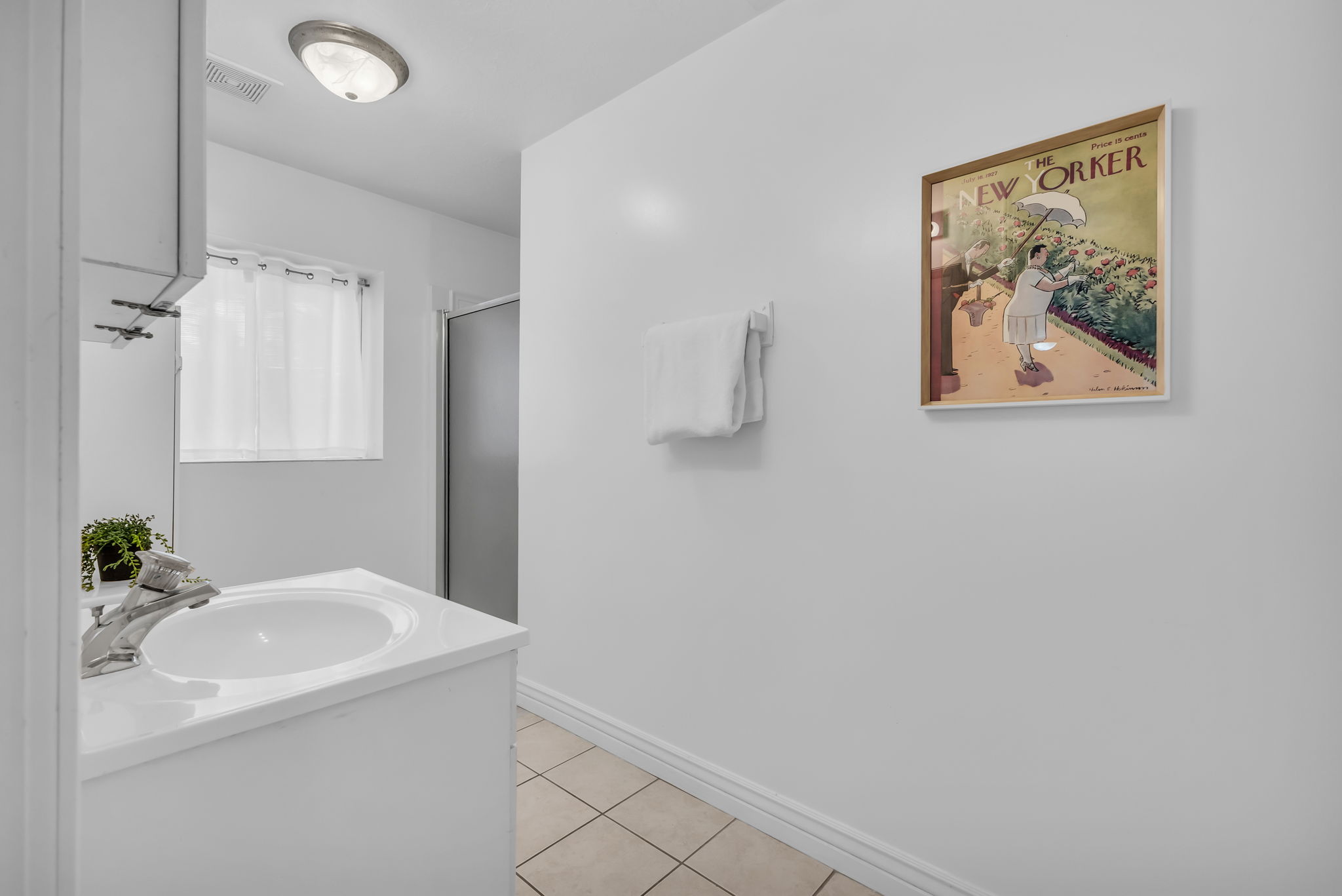 Bathroom featuring a single vanity with an integrated sink, chrome faucet, and white cabinetry