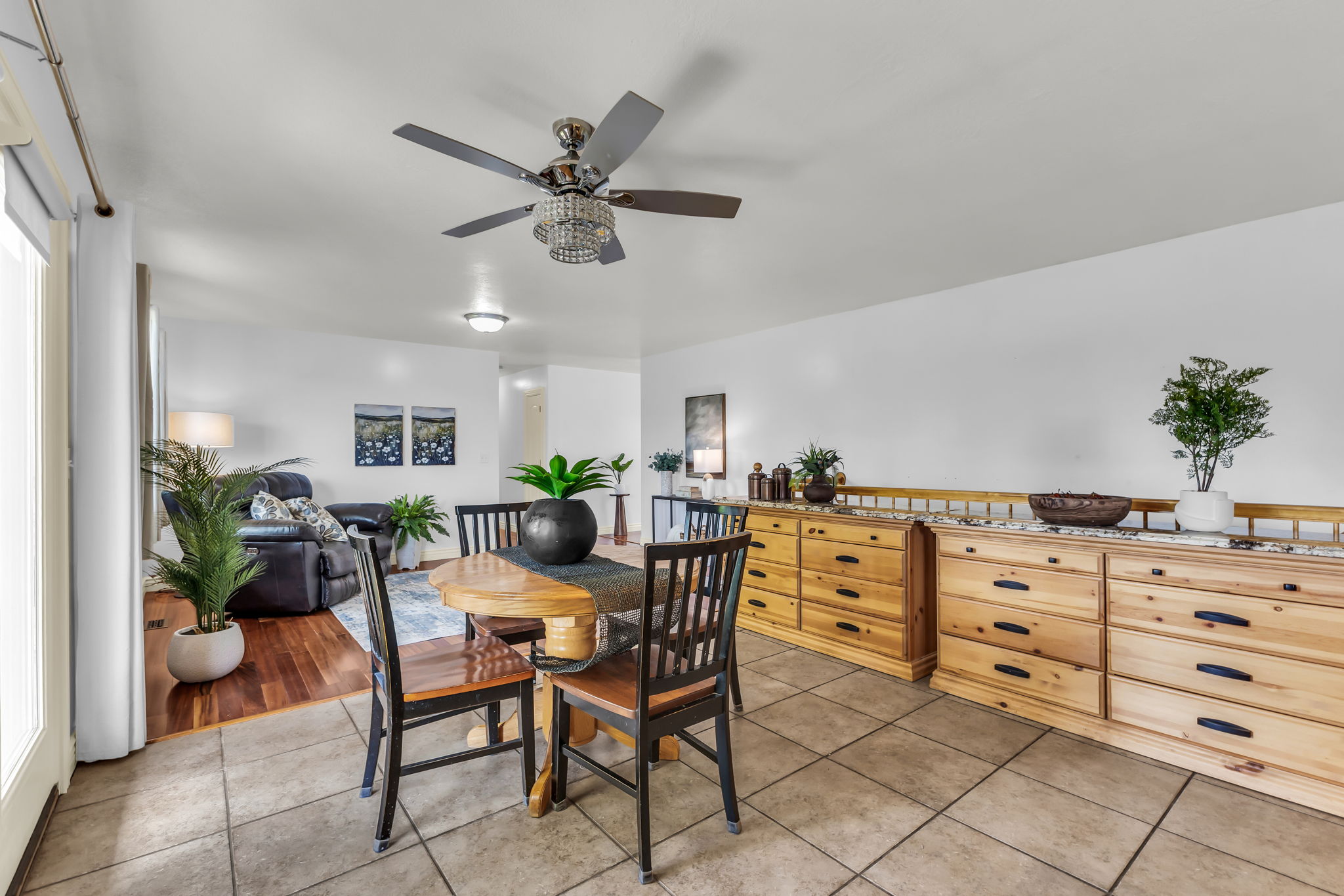 Spacious interior featuring a combination of tile and wood-finish flooring, a decorative ceiling fan, and white walls