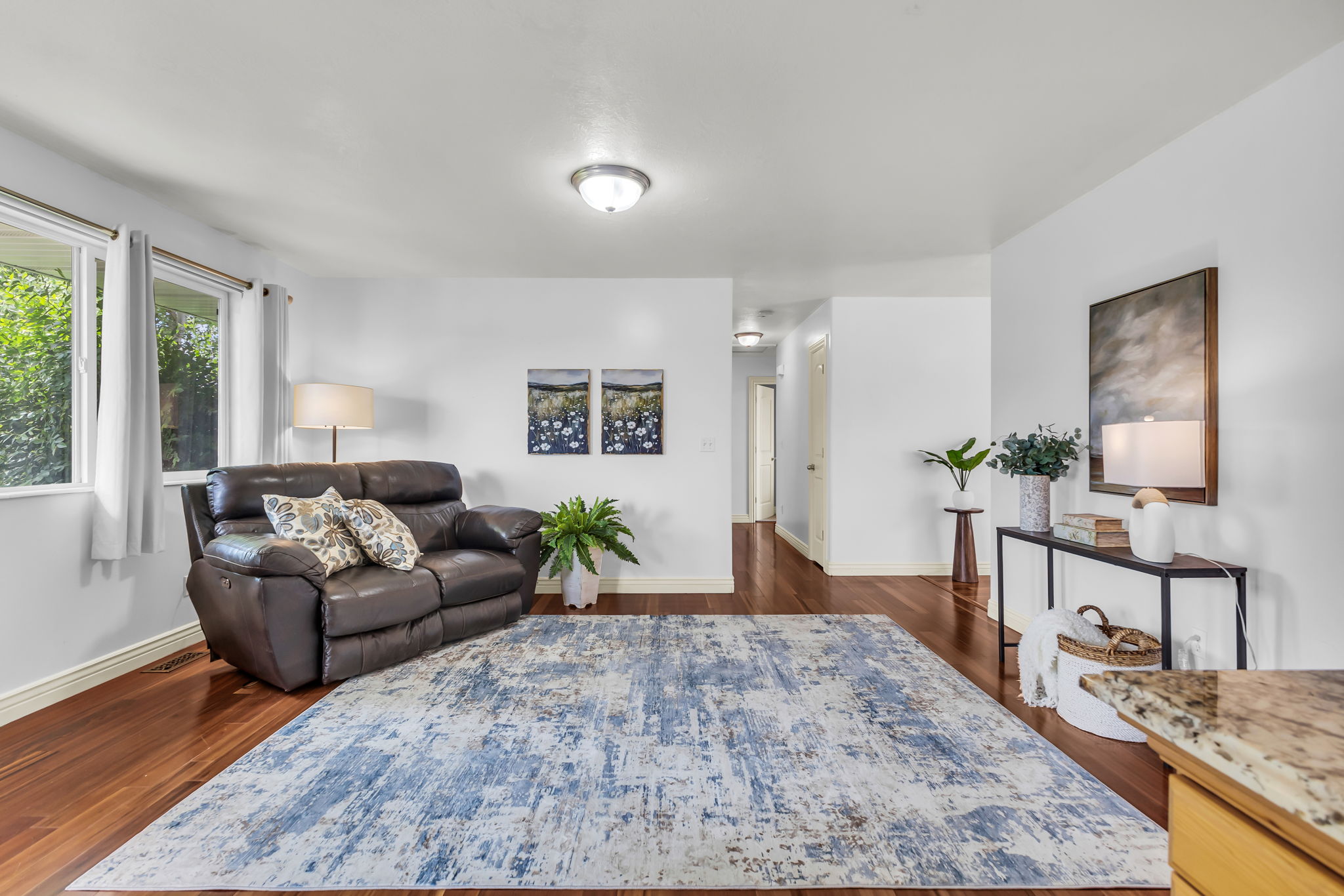 Bright living area featuring wood-finish flooring, white walls, and multiple windows