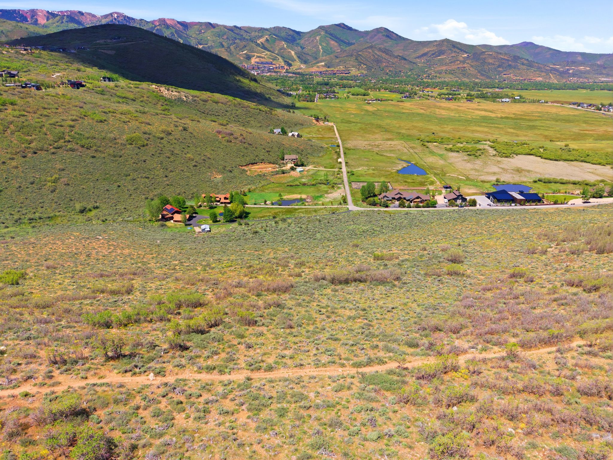 Expansive undeveloped terrain featuring natural vegetation, distant mountainous topography, and a clear blue sky