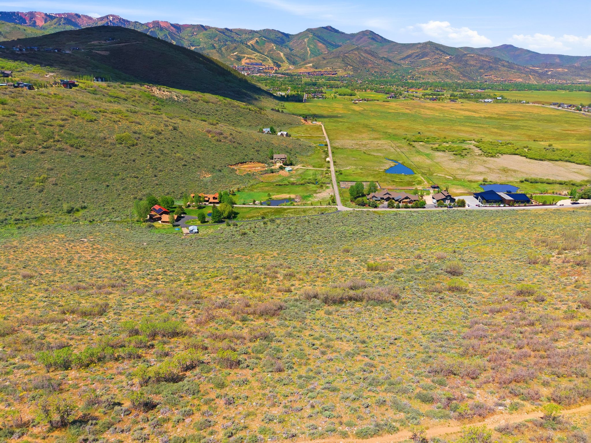 Expansive undeveloped lot featuring natural vegetation, a distant mountain range, and a clear sky