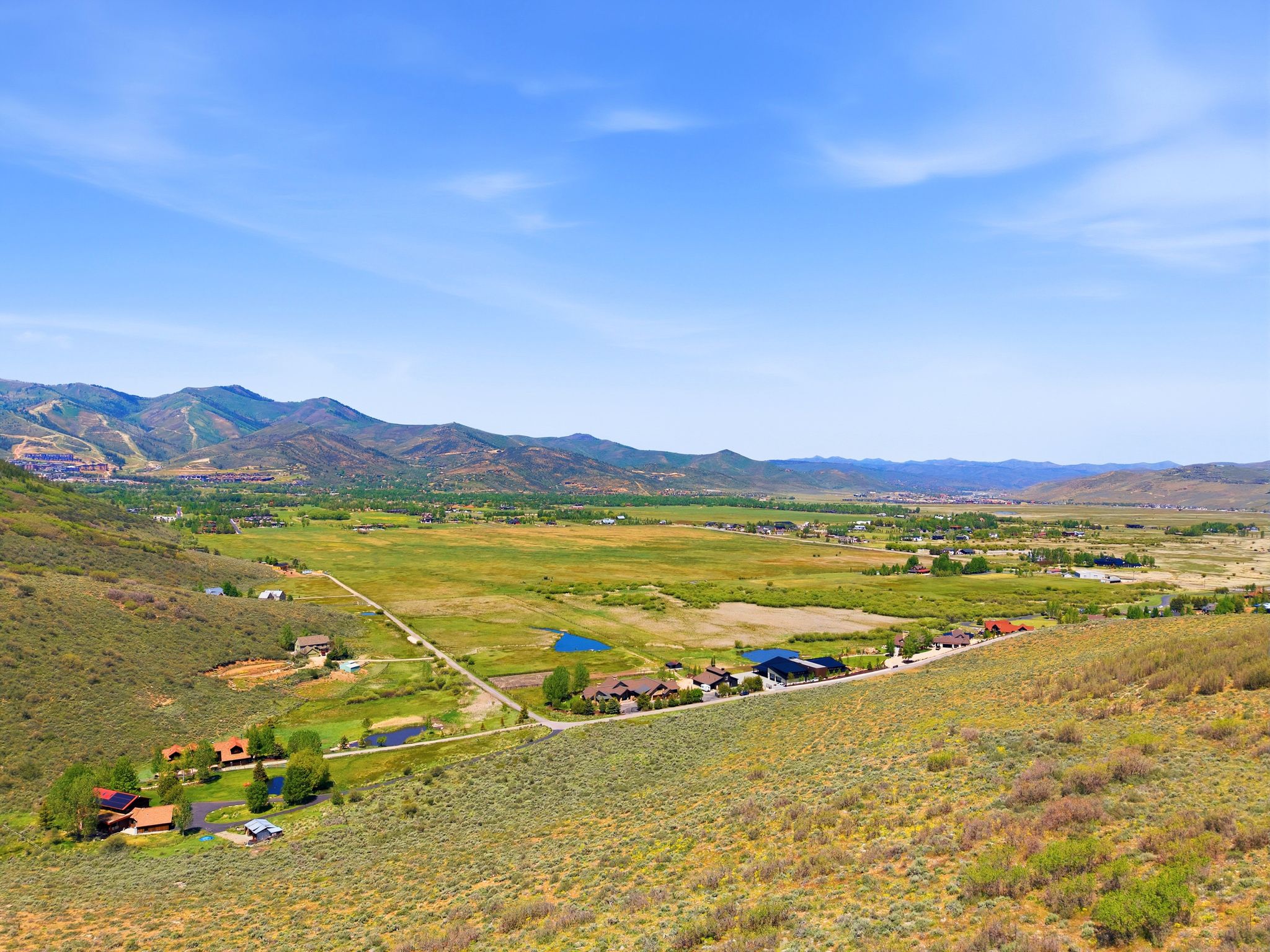 Expansive valley landscape featuring distant mountain ranges and scattered residential properties