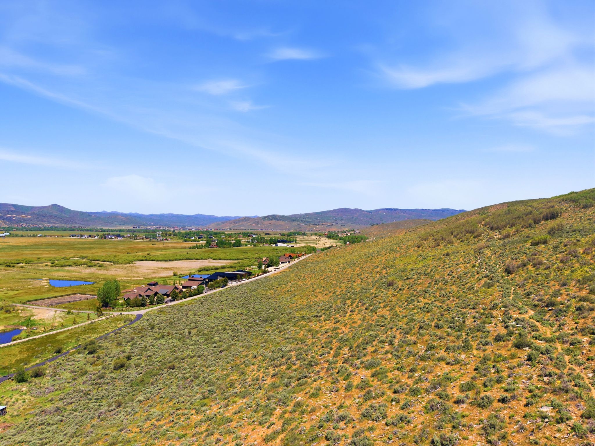 Expansive rural landscape featuring a mountainous backdrop, a broad valley, and multiple bodies of water