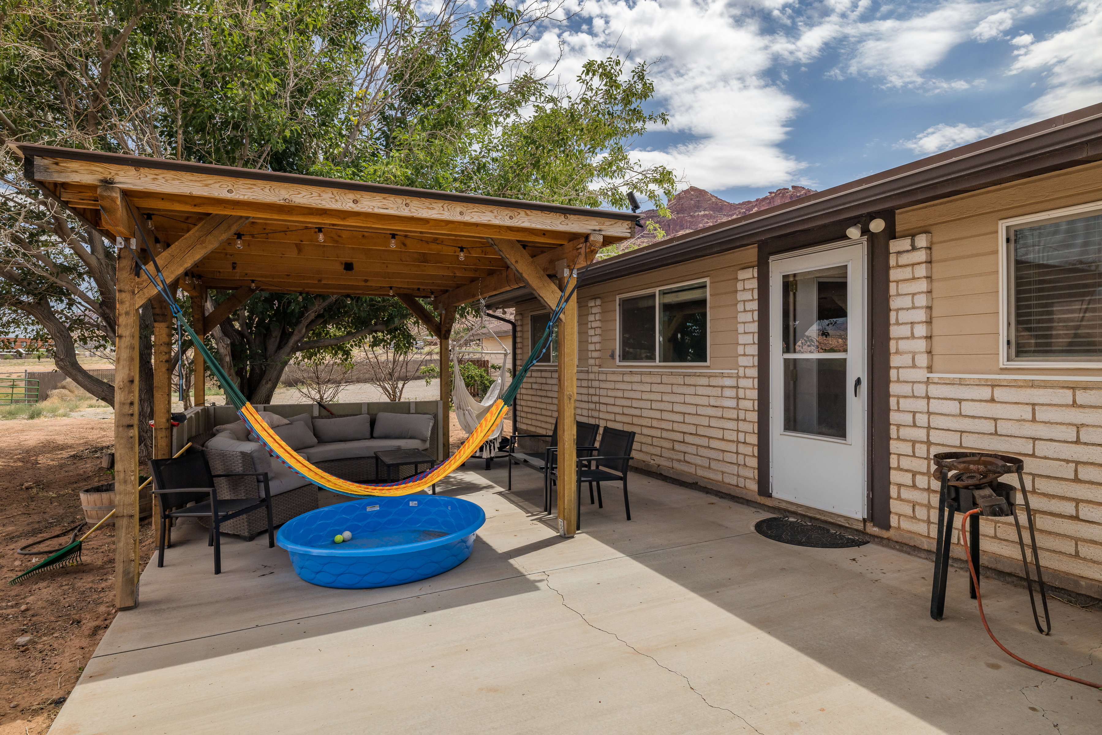 Outdoor living space featuring a wood-beam pergola with string lighting, a concrete patio, and a light brick and horizontal siding exterior