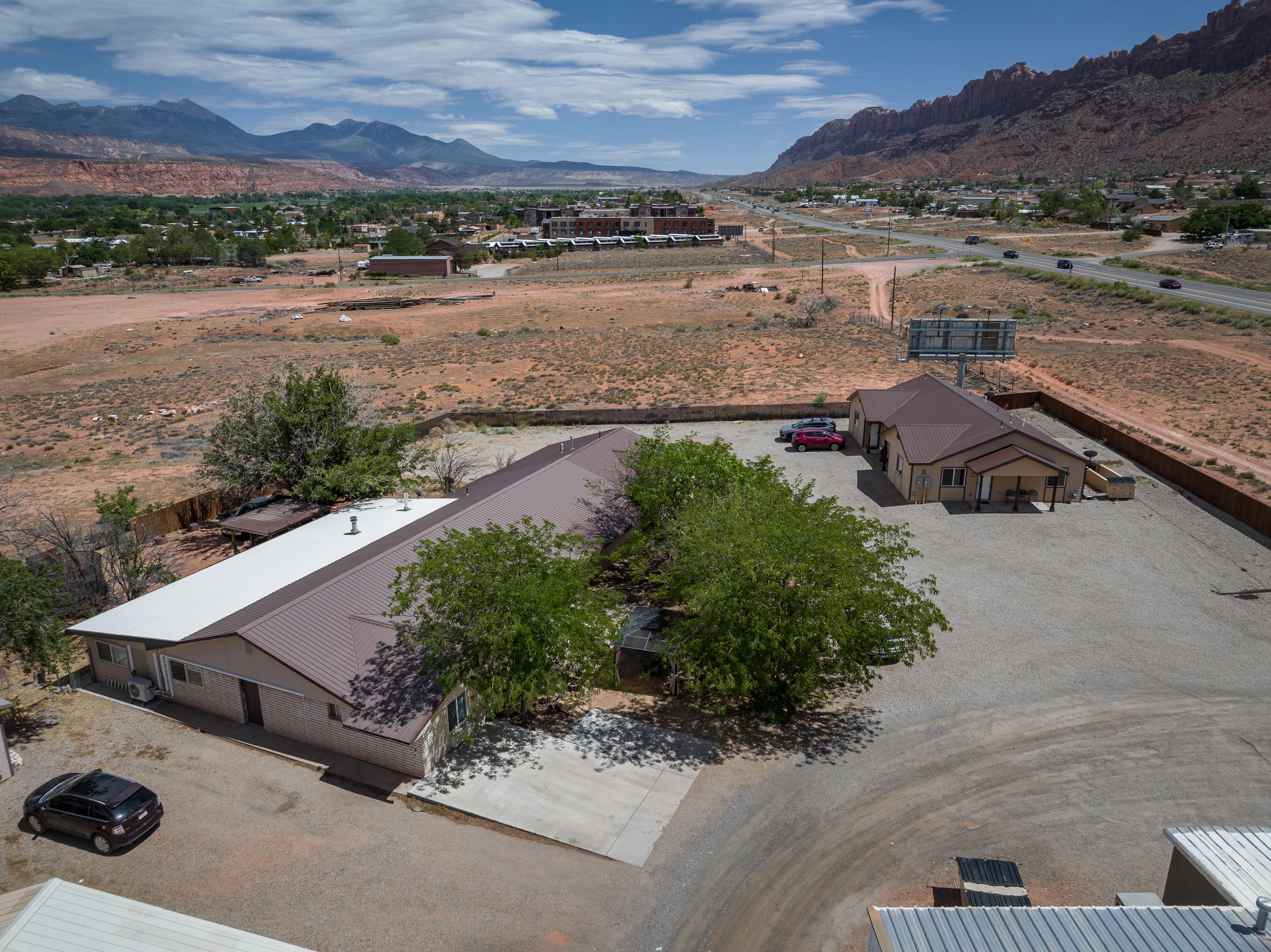 Expansive gravel lot featuring two structures with metal roofs and stucco exteriors