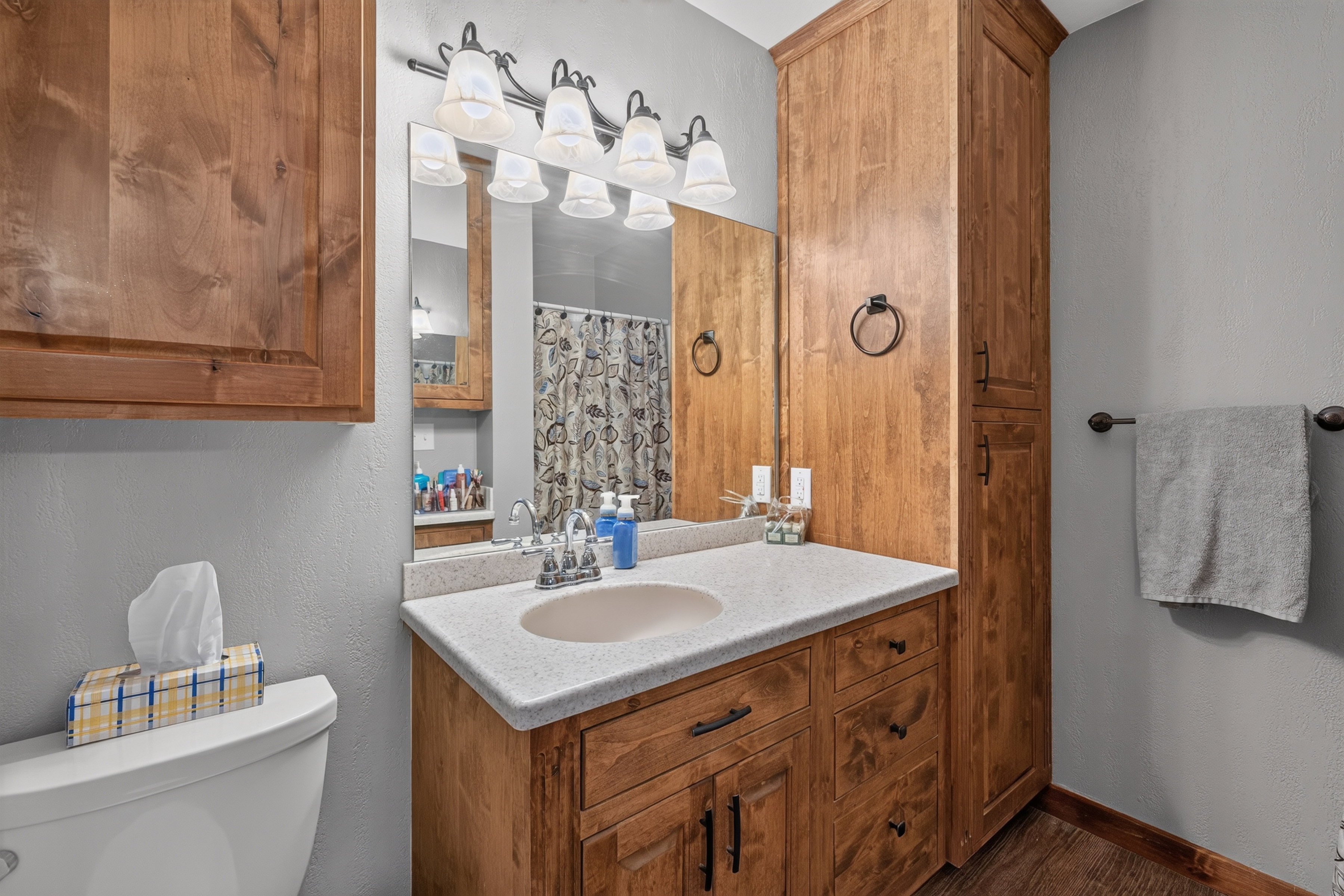 Bathroom featuring a single vanity with an integrated sink, a light-toned countertop, and wood-finish cabinetry