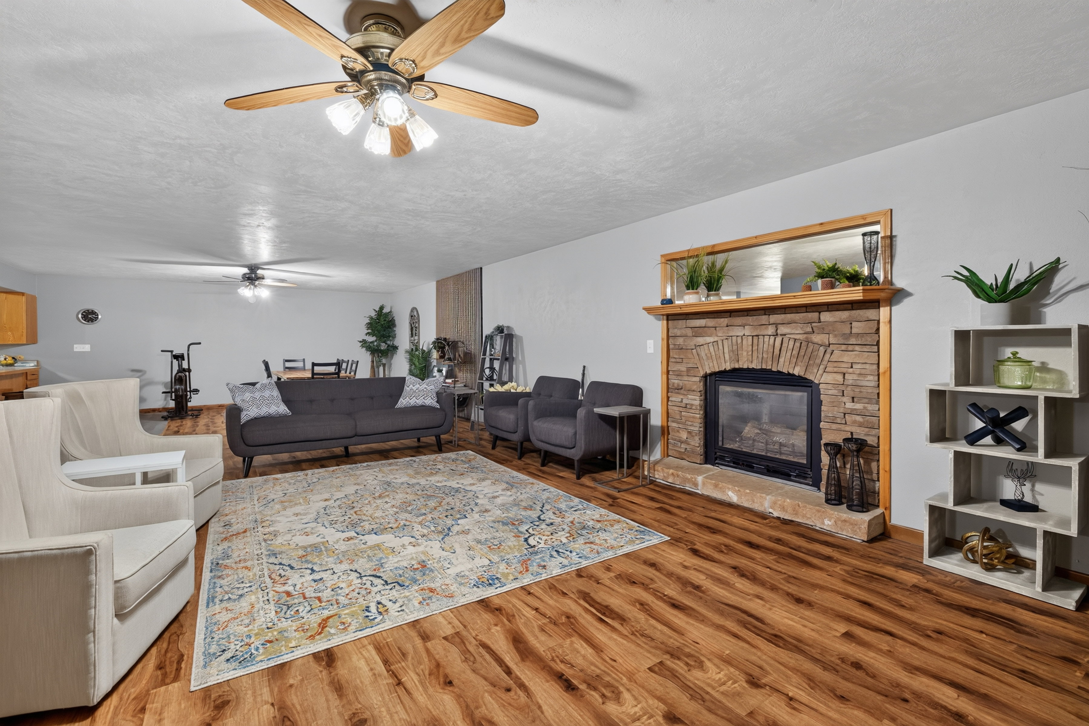 Spacious living area featuring wood-finish flooring and a stone-clad fireplace with a wood mantel