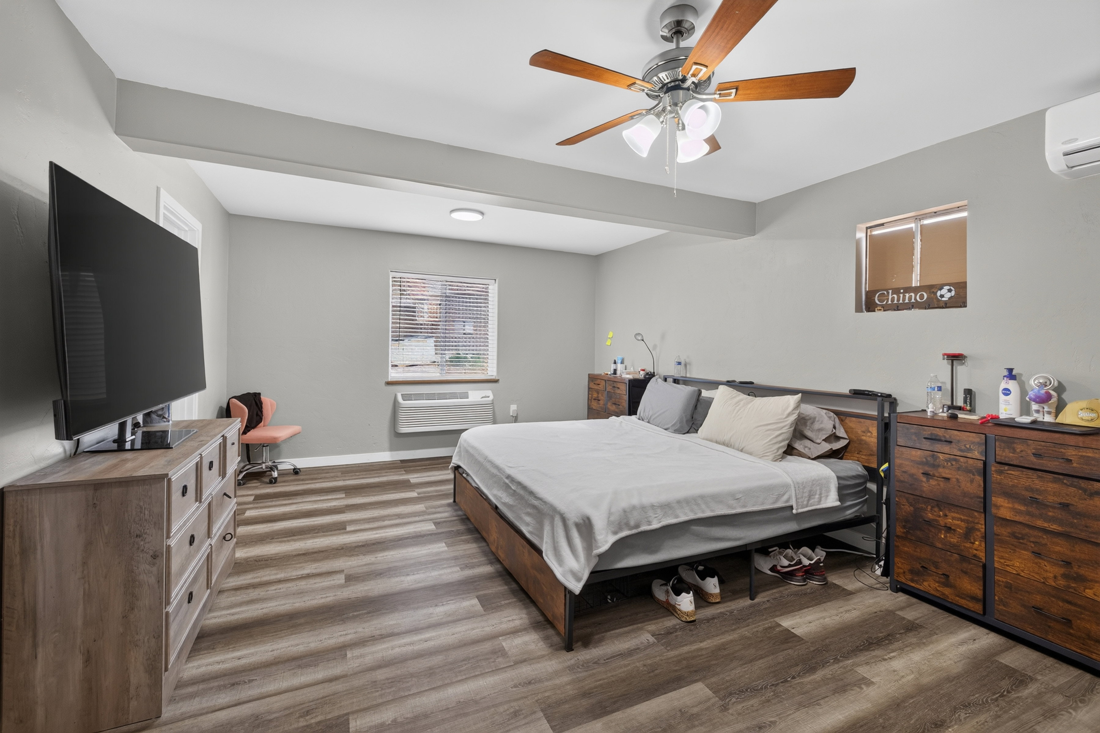 Spacious room featuring wood-finish flooring, a ceiling fan with integrated lighting, and neutral wall tones
