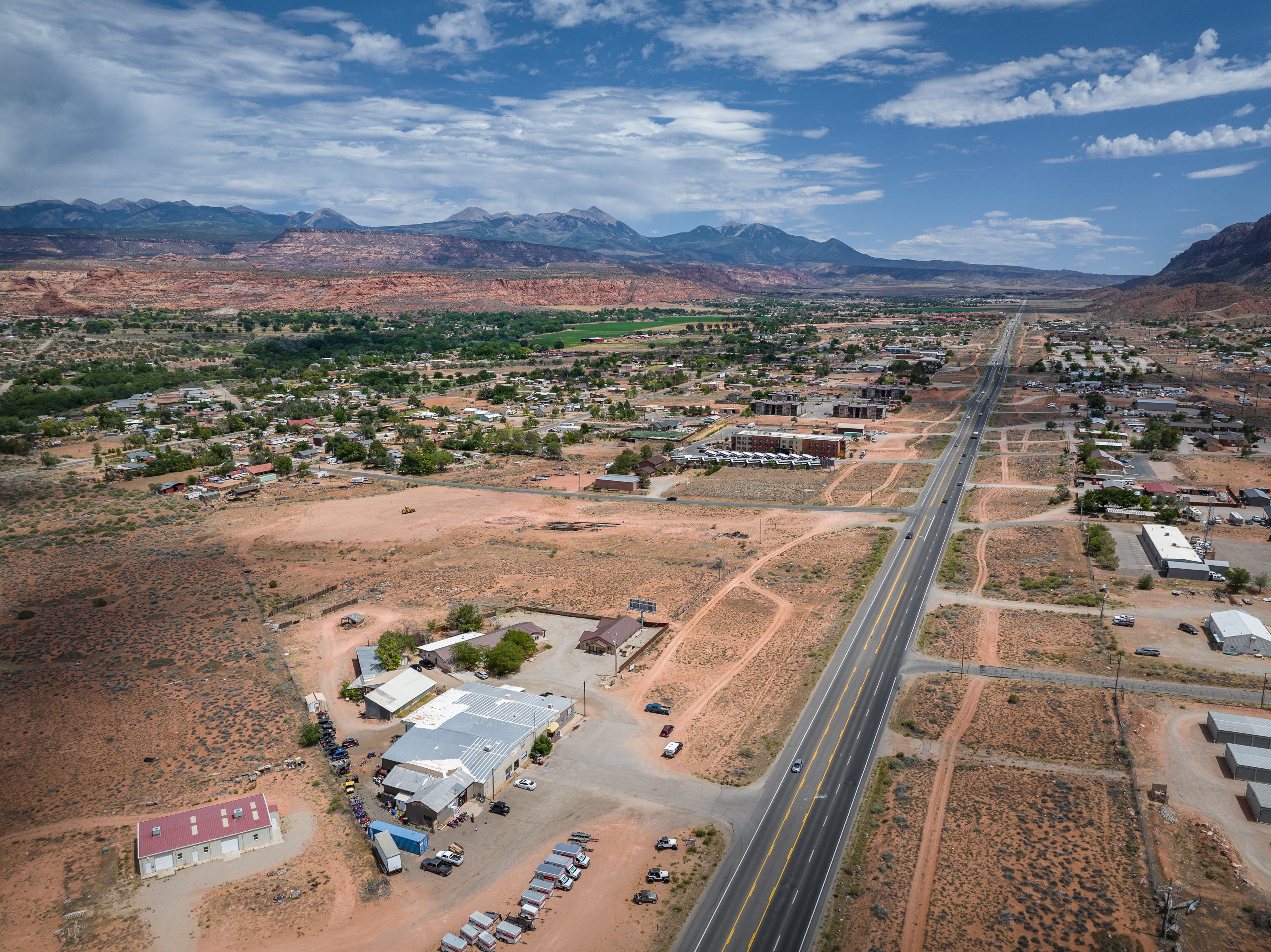 Expansive aerial perspective showcasing a commercial property with multiple structures, including a large building with a metal roof and an additional red-roofed structure