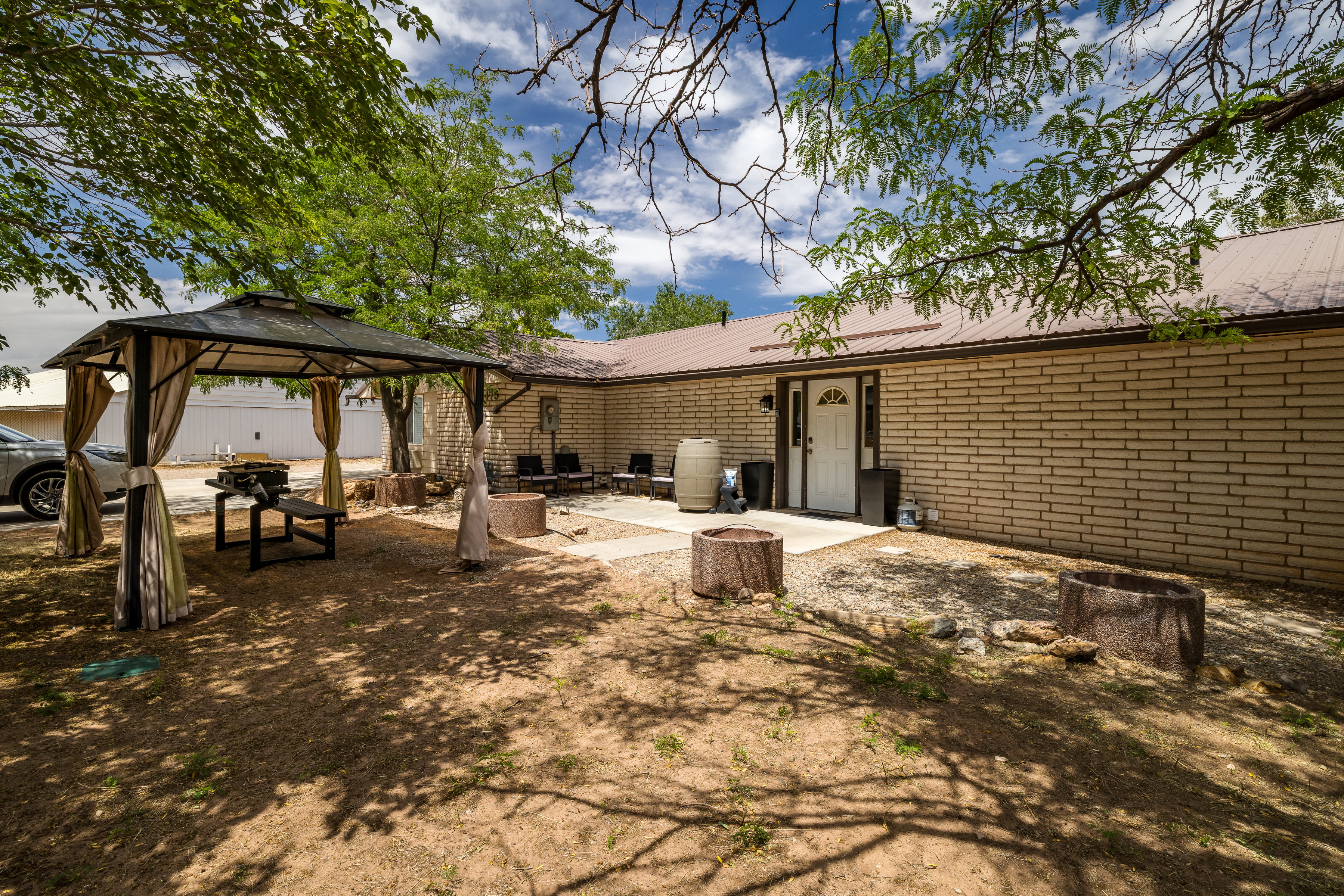 Exterior featuring a covered patio area with a gazebo, a brick facade, and a metal roof